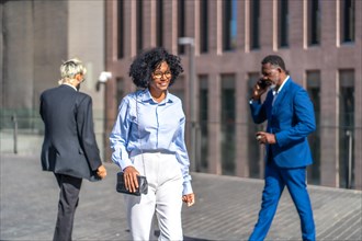 African businesswoman walking after work along the street with colleagues on the background