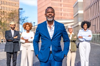 Portrait of a mature african american businessman and work team standing outdoors in a sunny day next to a financial building