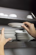Close up hand stacking white saucer shelf