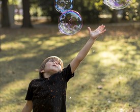 Kid trying catch soap bubbles