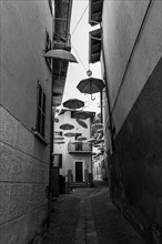 City Street in Porto Ceresio with Hanging Umbrellas in a Sunny Summer Day in Porto Ceresio