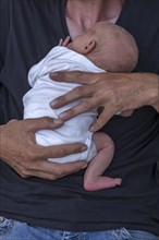 Newborn baby in the arms of the young grandfather