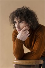 Curly man with brown blouse posing 3