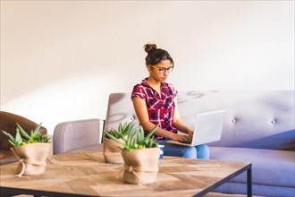 Horizontal photo with copy space of a Young casual woman working from home with laptop