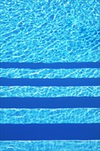 Water surface with light reflections and pool stairs in a swimming pool