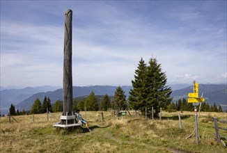 Wanderi sits by an artistic wooden sculpture on the Gerlitzen