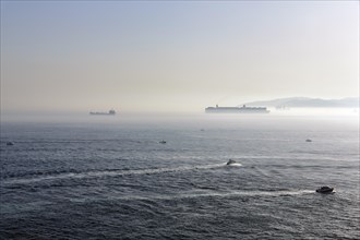 Cargo ships and motorboats in the haze