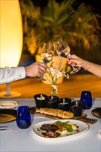 Close-up vertical photo of a couple toasting during a romantic night dinner
