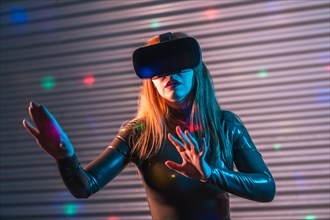 Blonde woman in an immersive game wearing Virtual reality goggles in an urban night space with neon lights