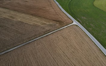 Drone view of a country road between harvested and green fields