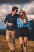Vertical photo of a stylish couple embracing on a hill in the mountain