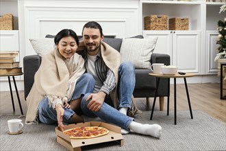 Couple blanket watching tv eating pizza