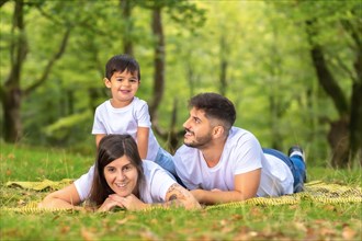Boy piggybacking his mother lying in the grass with his parents