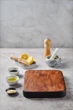Empty wooden chopping board surrounded with kitchen utensils and bowls