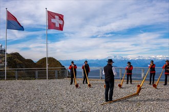 Group of Musicians Playing on Horns of the Alps with Mountainscape and View over Snow Capped Monte Rosa in a Sunny Day in Monte Generoso