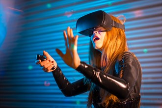 Surprised woman immersed in a vitual experience using VR goggles in an urban night space with neon lights