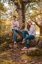Vertical portrait of a casual couple in denim clothes sitting on a forest