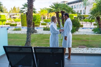 Horizontal photo with copy space of a couple with bathrobe drinking water in an outdoor pool side