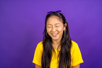 Studio photo with purple background of a chinese woman laughing with eyes closed