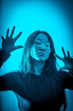 Studio photo with blue background with neon lights of a cyber chinese woman gesturing in a metaverse space