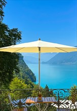 Grandhotel Giessbach with Terrace and Parasol with Furniture and View over Lake Brienz with Mountain in a Sunny Summer Day in Brienz