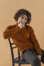 Curly haired man with brown blouse posing 12