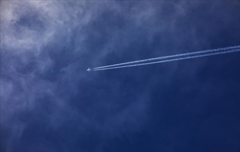 Commercial aircraft with contrails in the blue sky