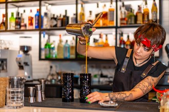 Young alternative professional bartender working on a bar preparing cocktails