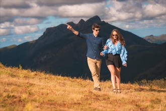 Stylish elegant couple observing nature and walking along the mountain