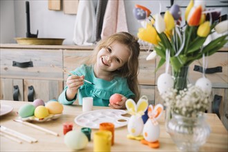 Cute girl painting eggs easter table