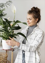 Medium shot woman holding plant pot