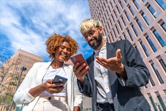 Low angle view portrait of happy multi-ethnic business people smiling while using phone outdoors