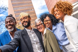 Low angle side view of multi-ethnic business people smiling and taking a selfie outdoors