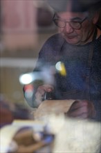 Senior expert luthier artisan violin maker carve sculpt chisel ribs of a new classical model cello in workshop Cremona Italy