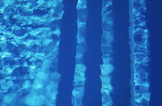 Water surface with light reflections and pool stairs in a swimming pool