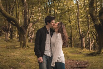 Horizontal portrait of a young couple kissing in the forest alone