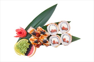 Overhead view of roll with salmon with cream cheese and shrimp on top served on bamboo leaves