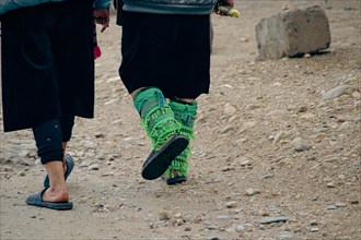 Close up to two black hmong women walking and wearing their ethnic leg ornaments
