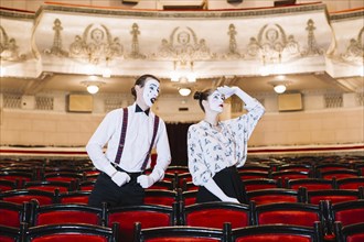 Male mime looking female mime looking up auditorium