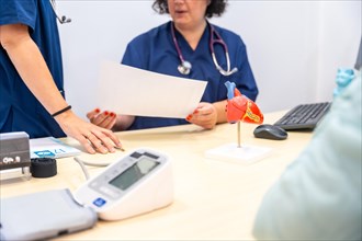 Nurse and doctor sharing paperwork in a cardiology office with a plastic model of heart on the table