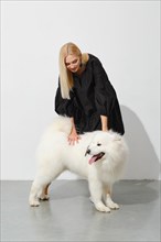 Lovely woman petting her samoyed dog in a bright room