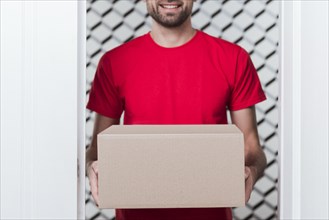 Front view delivery man wearing red uniform close up box