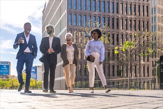 Low angle view of multiracial group of business people walking along a financial district
