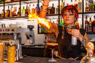 Bartender using torch to flaming the decoration of a cocktail in the counter of a bar