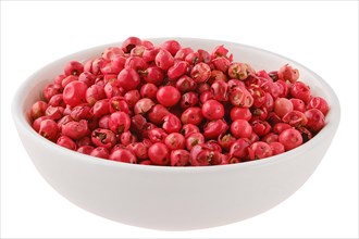Fragrant pink pepper seeds in a white ceramic bowl isolated on white background
