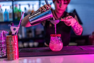 Close-up of a woman preparing a cocktail in the counter of a nightclub