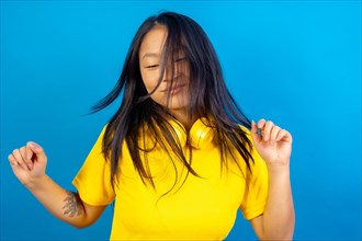 Studio photo with blue background of a chinese woman with headphones dancing freestyle