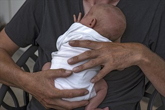 Infant in the arms of the young grandfather