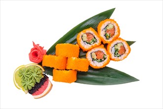 Overhead view of salmon roll with avocado and caviar on top served on bamboo leaves