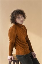 Curly man with brown blouse posing 2